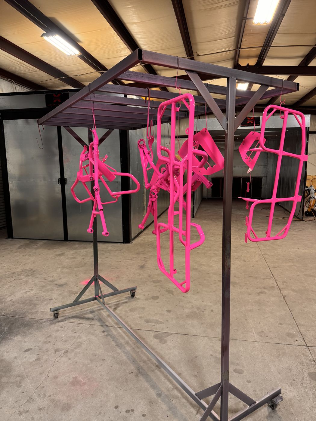 Hot pink powder coated parts curing on a rack