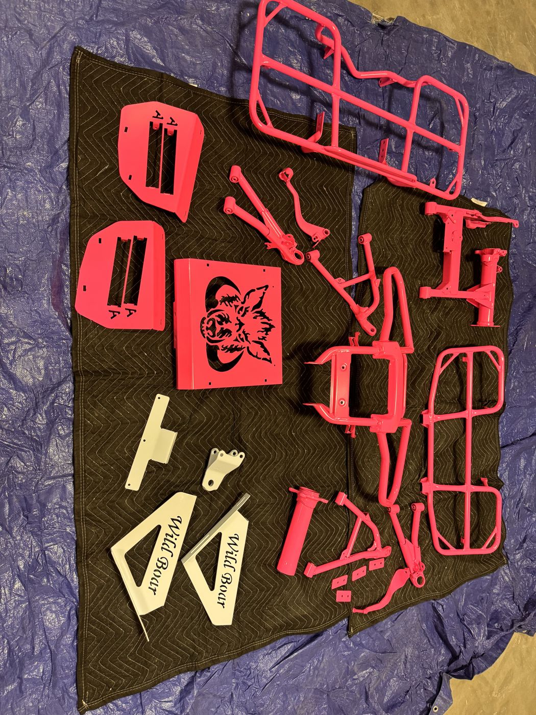 Pink and cream powder coated Wild Boar parts laid out after coating