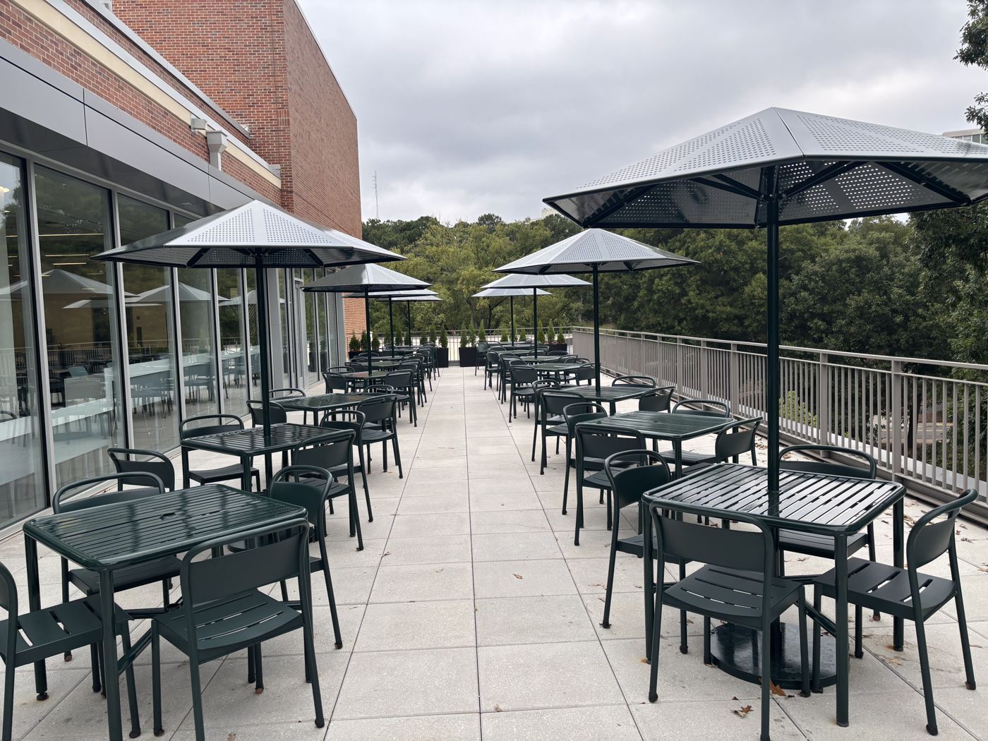Green powder coated patio tables, chairs and umbrellas on a rooftop terrace